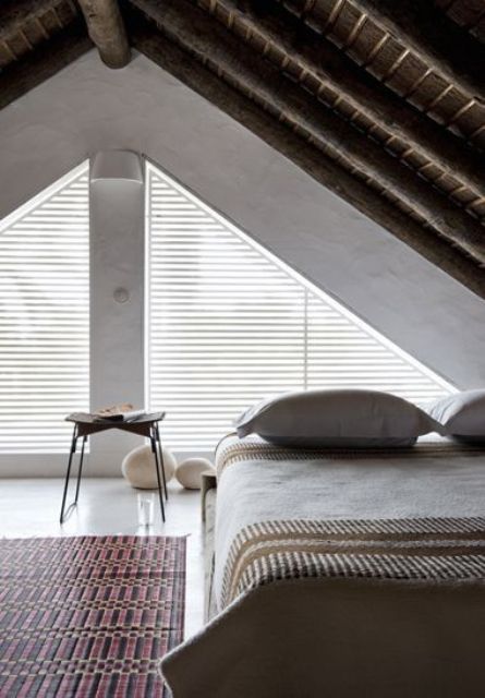 an attic bedroom with a bed placed in the corner, a zen feel and touches bring peacefulness to the space