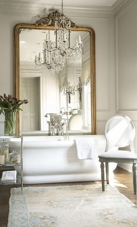an oversized mirror in a vintage frame makes the bathroom exquisite, and a crystal chandelier adds to the space