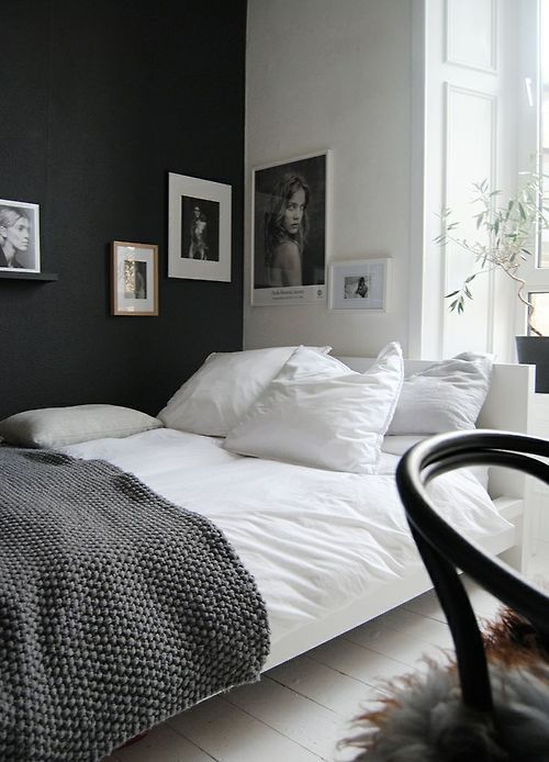 a Scandinavian bedroom in black and white, with proper artworks covering the corner