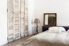 22 a minimalist sleeping space with old shutters as wardrobe doors that add texture and interesting to the space