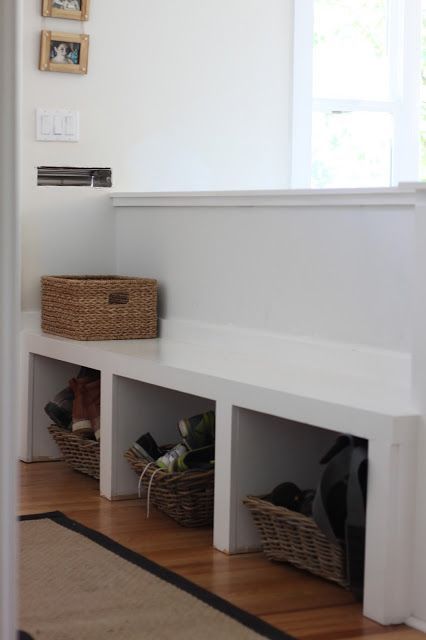 a pony wall with a bench and open storage that separates the entryway and living space