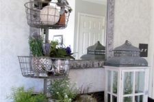 24 a console with a faux nest with eggs, a lantern and a stand with potted greenery and flowers