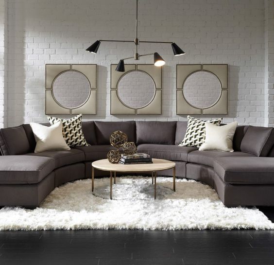 a laconic brown rounded sectional sofa is the base of this room, and everything is built around it