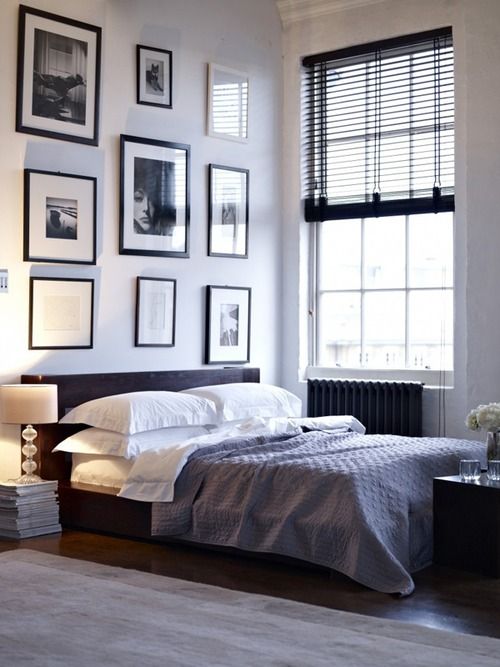 a laconic masculine sleeping space with a gallery wall and dark touches here and there