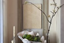 24 a stylish art piece of a porcelain shell, moss and magnolia cones for a chic modern look
