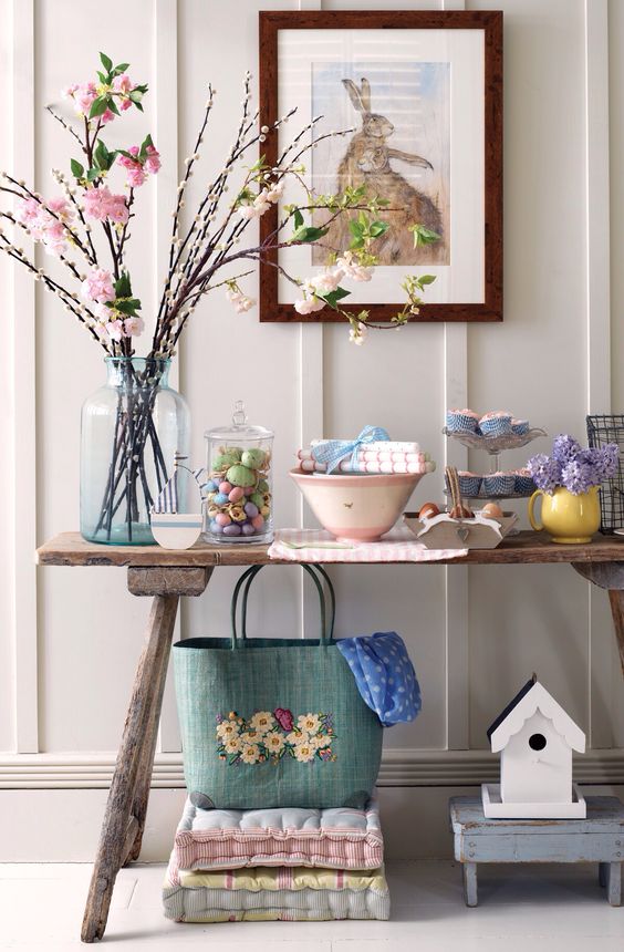 a console with blooming branches, colorful eggs in a jar, bold flowers and textiles
