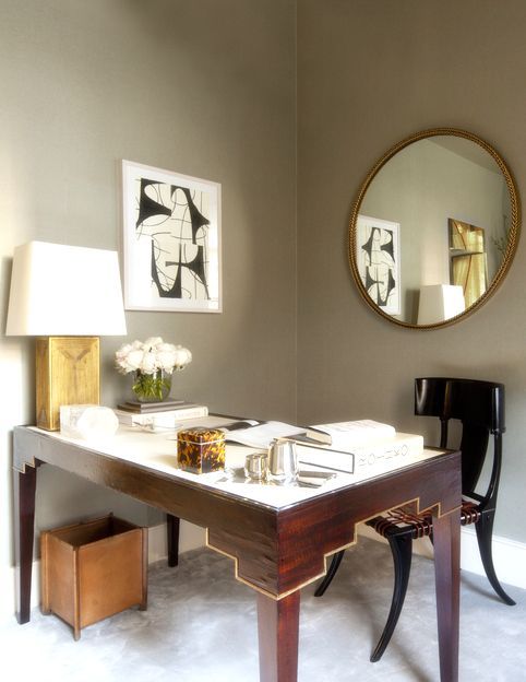 a mid-century modern home office with an artwork and a large round mirror on the wall
