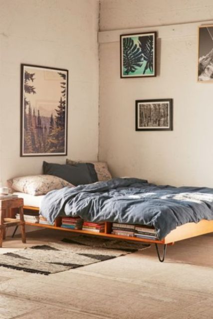 a small industrial bedroom with a hairpin leg bed with storage inside and various artworks