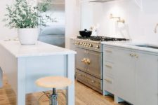 pastel freestanding kitchen cabinets with brass touches and a kitchen island on tall legs for a lightweight feel