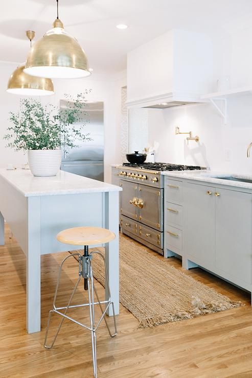 pastel freestanding kitchen cabinets with brass touches and a kitchen island on tall legs for a lightweight feel