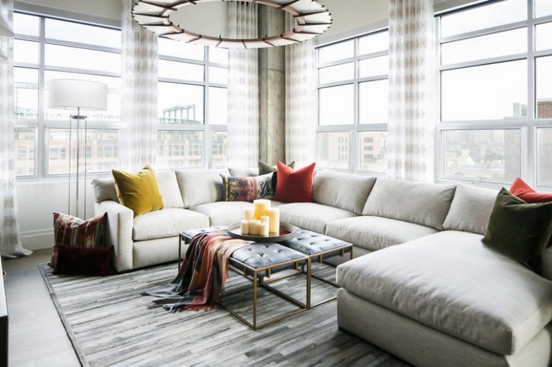 Large windows bring much light inside, and a large corner sofa with a double upholstered bench creates a cozy space