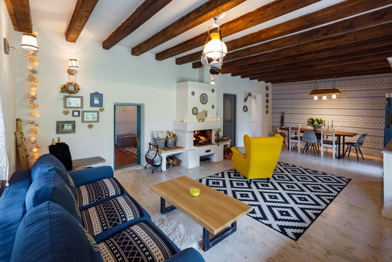The living room and dining space are united into one layout, with wooden beams and colorful furniture