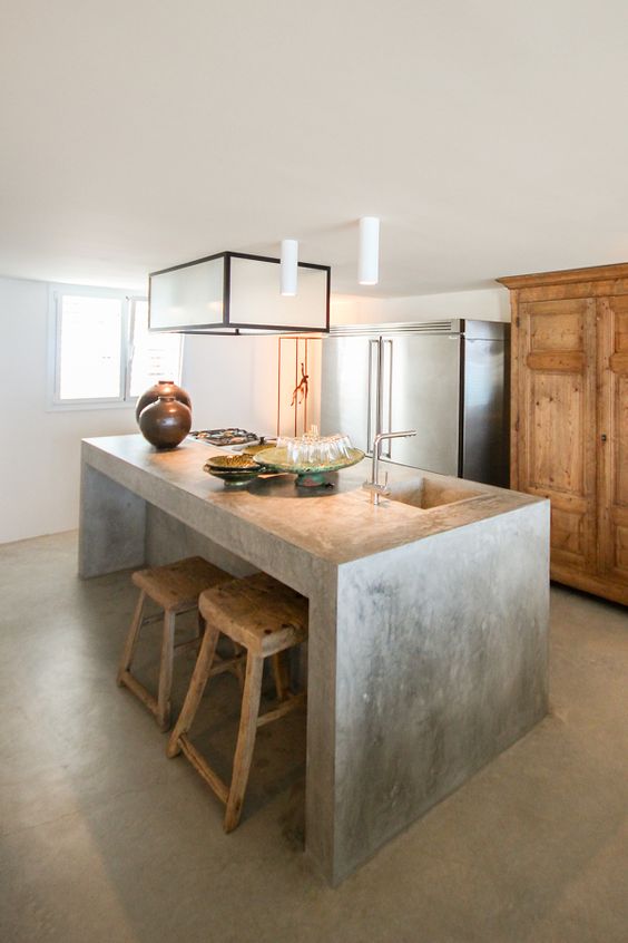 a simple concrete kitchen island with a breakfast space is also an industrial idea but brings a modern vibe
