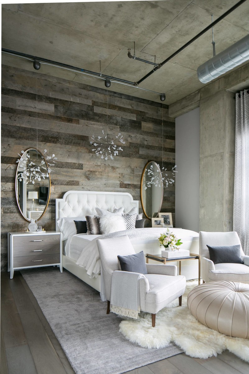 The master bedroom features exposed pipes, reclaimed wooden walls, cute farmhouse furniture and some glam touches like chandeliers