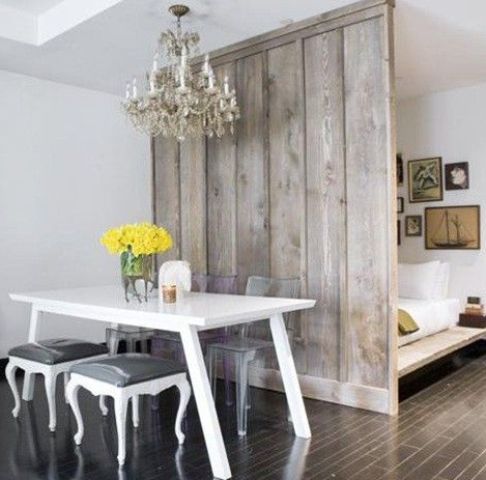 a rustic grey wooden screen makes the sleeping space more private and adds coziness to the shabby chic space