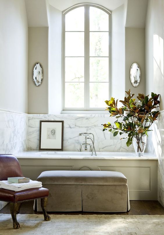 a vintage space with a bathtub clad with marble and the walls around it clad with the same for a refined feel