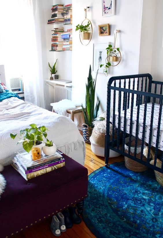 a boho shared master bedroom with a nursery nook with a navy crib and baskets for storage