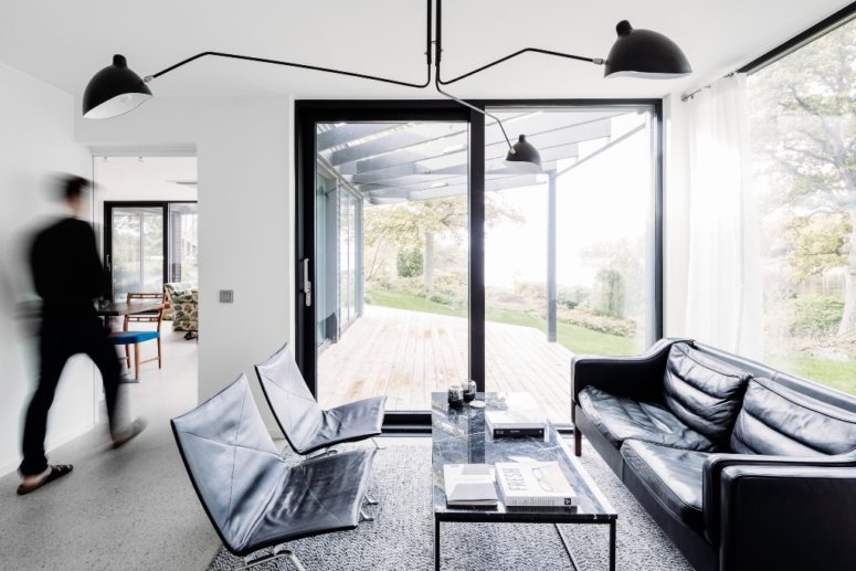 The living room is done in black and white, with modern and minimalist furniture and much glazing