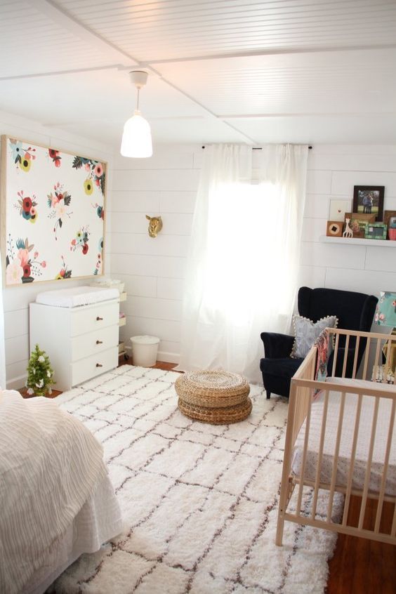 a boho master bedroom with a crib, a comfy chair with a footrest and a changing table in the corner