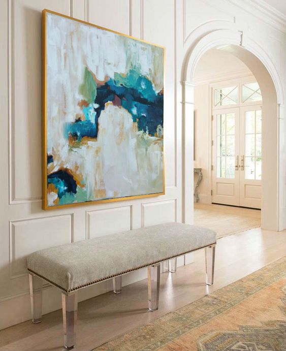 a modern bench with acrylic legs, creamy upholstery and an abstract artwork with creamy shades