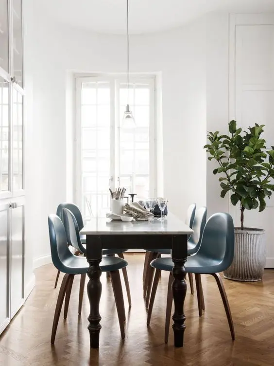 A vintage black and white table and mid century modern blue chairs on curved legs to a bold look