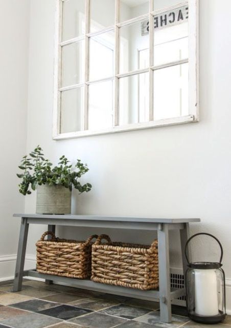 a grey vintage bench with an additional shelf and baskets for storing various things and shoes