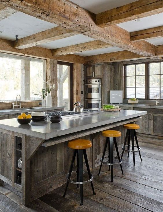 a large kitchen island of reclaimed wood and with a polished concrete countertop with a breakfast space