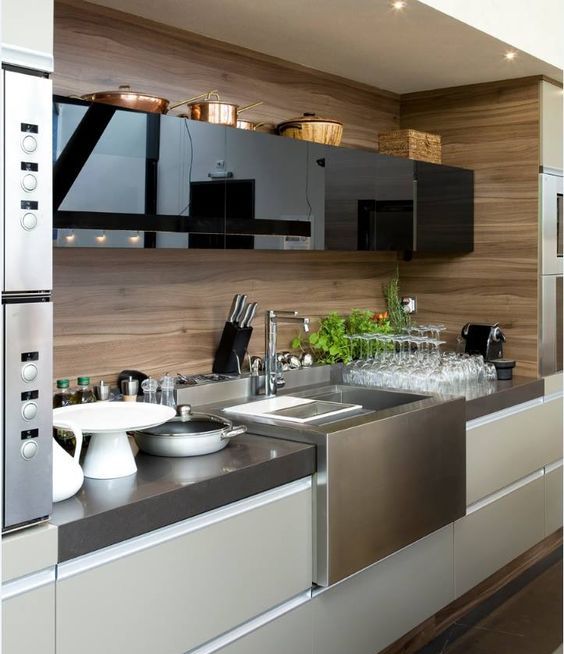 A minimalist kitchen with glossy black and matte off white cabinets plus a plywood backsplash