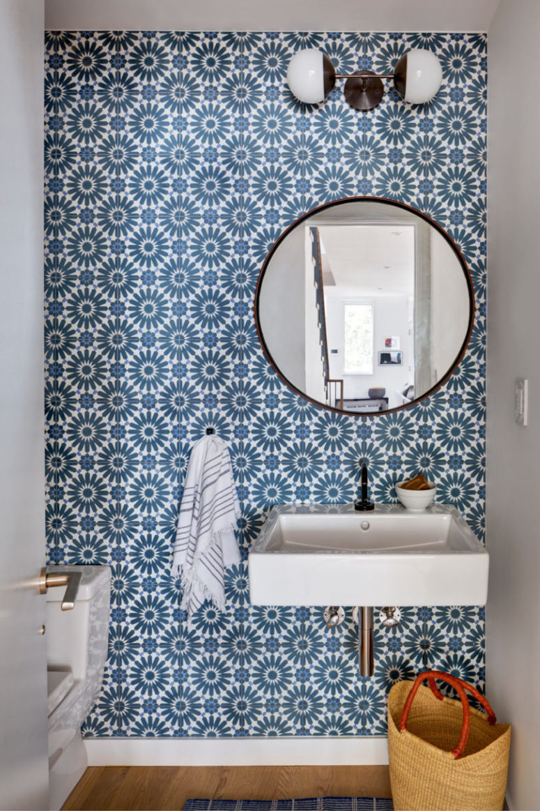 The powder room shows off a statement wall with gorgeous blue printed tiles and a round mirror
