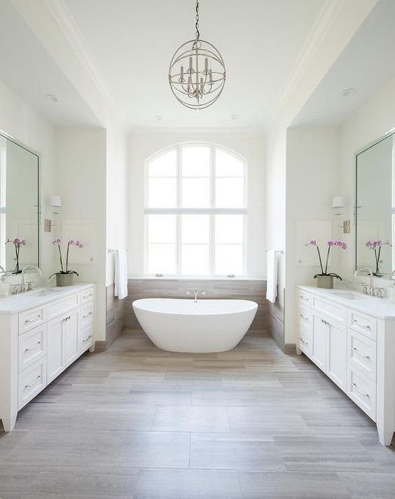 a white bathroom is accented with wood and the backsplash saves the window and makes the bathroom feel spacious