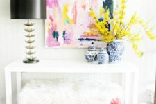 08 a white console, pink and fur stools and a bright abstract artwork plus bold flowers for a cool look