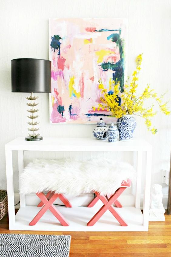 a white console, pink and fur stools and a bright abstract artwork plus bold flowers for a cool look