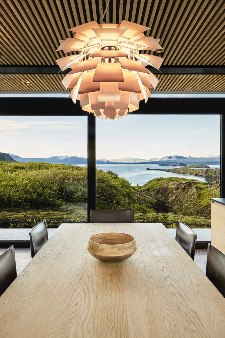 The dining space is done with black leather chairs and a light-colored wooden table and look at those views