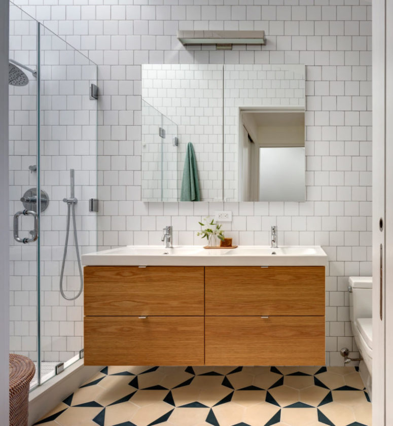 The bathroom is serene, with white tiles and a floating light-colored wood vanity