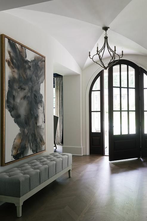 a modern entryway with a grey tufted bench and a creamy and grey artwork over it for a bold look