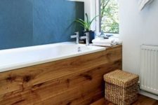 11 large slate tiles used as a bathtub backsplash create a bold contrast to light-colored wood