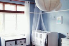 13 a peaceful blue master bedroom with a baby’s corner with a crib and a changing table with baskets