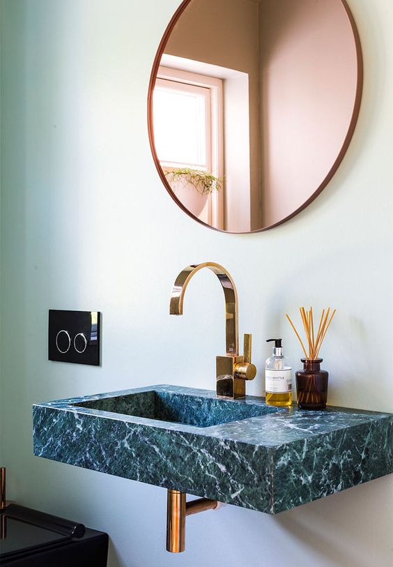 a stunning green marble sink with luminaire and mirror in brass