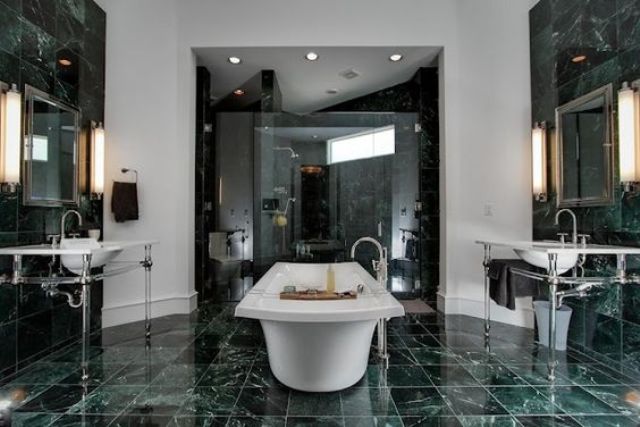 a gorgeous elegant bathroom with green marble tiles on the walls and floor and in the shower