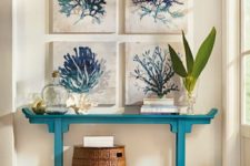 16 a coastal entryway with a turquoise console table, a basket and a gallery wall of watercolor sea artworks