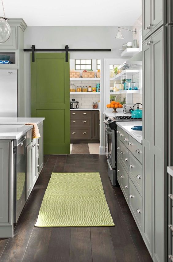 a grass green painted barn door separates the kitchen and pantry and adds a cute colorful touch