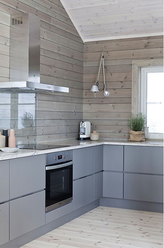 a minimalist chalet kitchen with sleek grey cabinets and wooden plank walls plus a glass screen