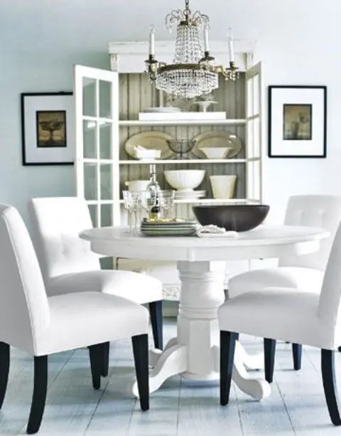a white vintage round table and modern chairs with white upholstery for a refined and chic space