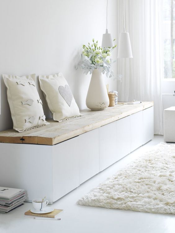 a modern white bench with a wooden plank top and much storage space inside