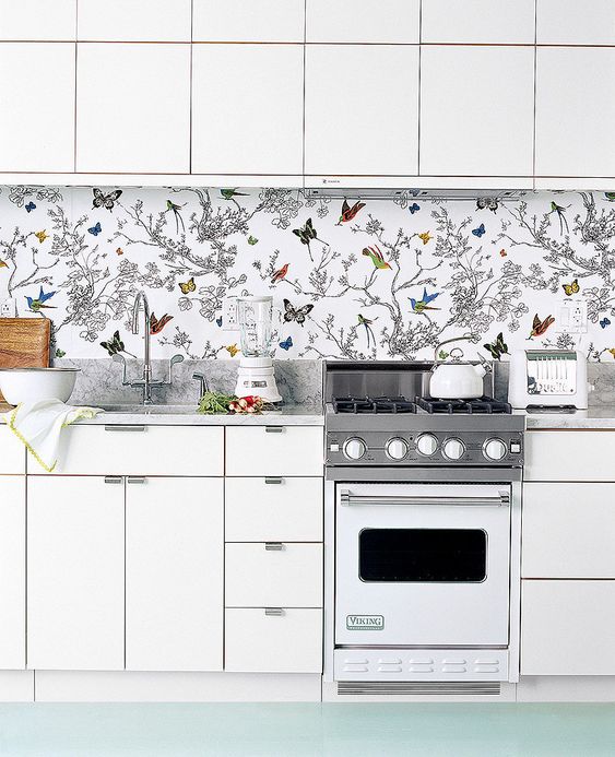 To avoid a boring look in an all white kitchen, rock a colorful wallpaper backsplash with butterflies and birds