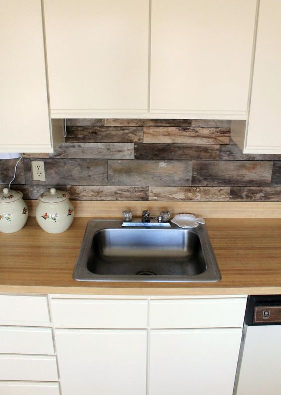 Cream sleek cabinets, a light colored wood countertop and a backsplash of reclaimed wood for a unique look