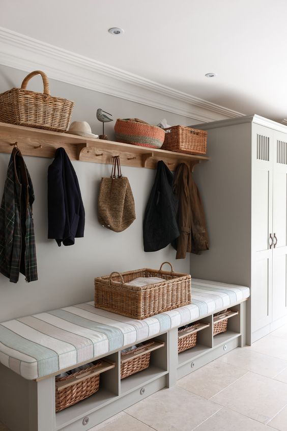 a bench with a striped mattress on top and some woven baskets as drawers inside