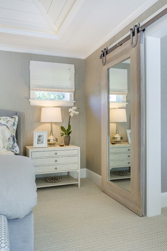 a light-colored barn door with a large mirror can be used for dressing up in the bedroom