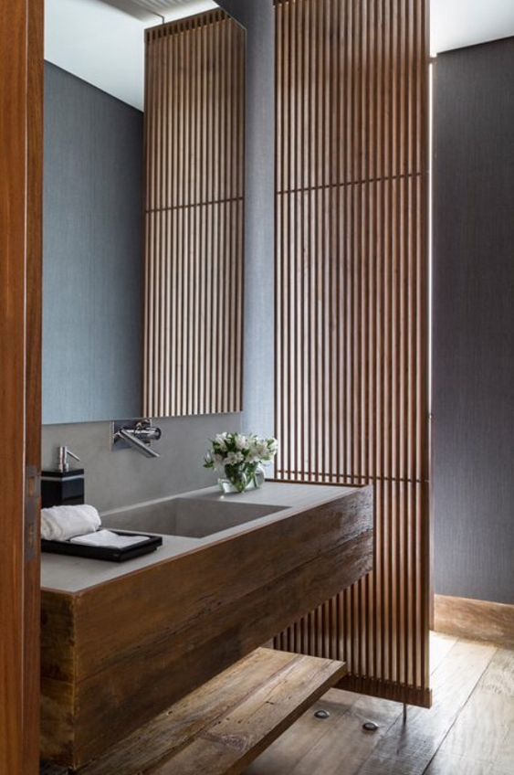 a vertical wooden plank screen separates the bathroom into two parts but lets light in
