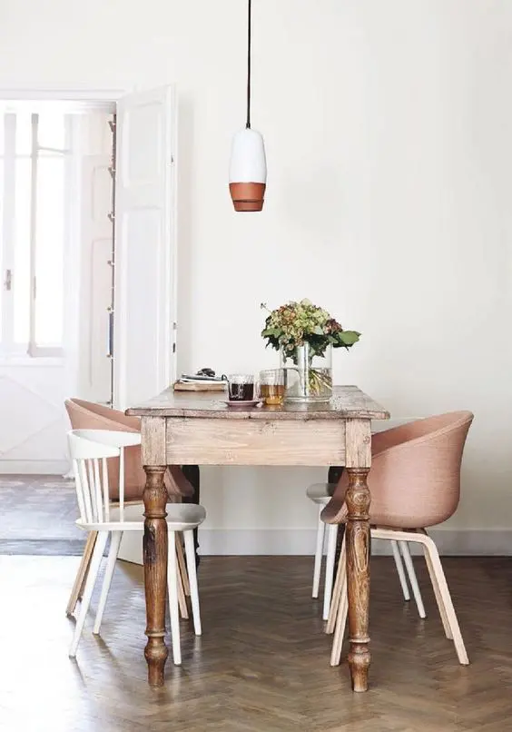 a vintage rustic table and white and blush modern chairs that match in colors
